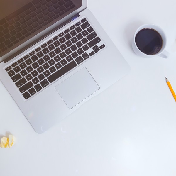 grafika przedstawia biurko a na nim laptop, ołówek, żółte karteczki biurowe oraz czarną kawę w białej filiżance